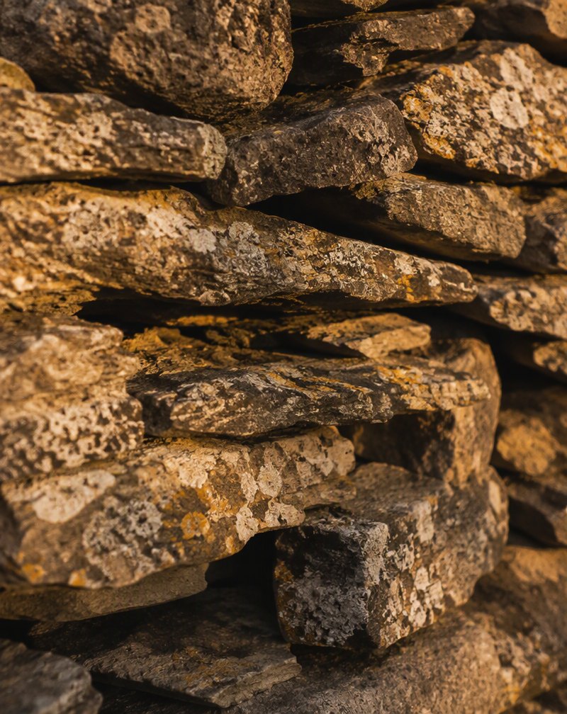Hand-stacked dry-stone wall with lichen, warm raking light