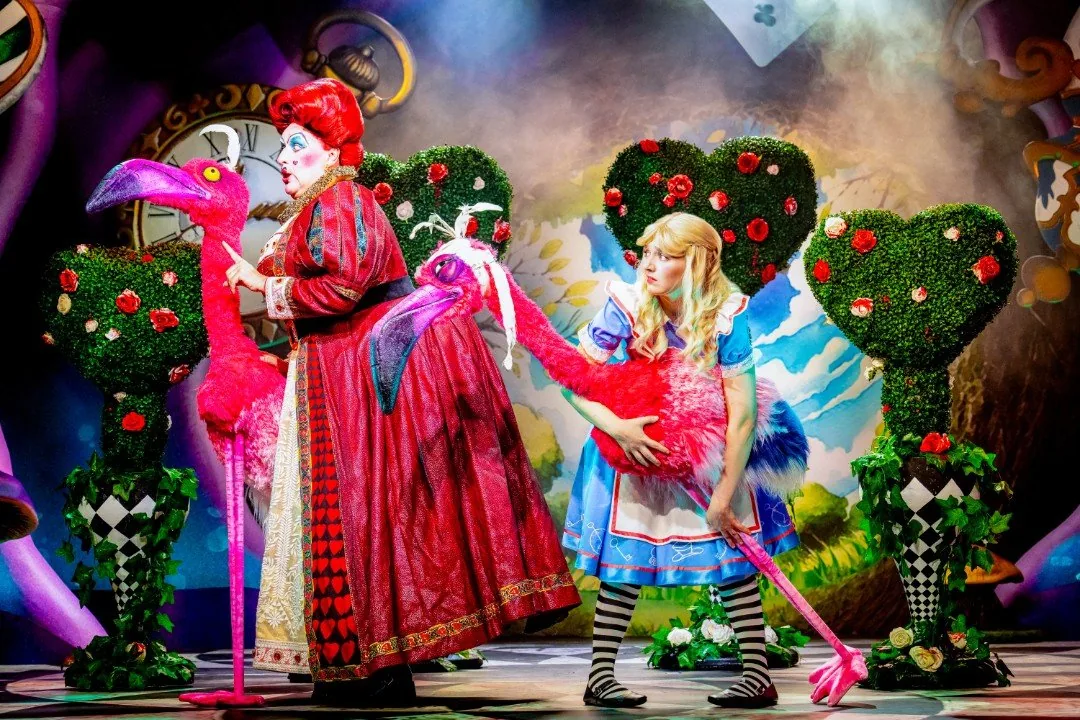 Alice faces the formidable Queen of Hearts in a dramatic stage scene from the production