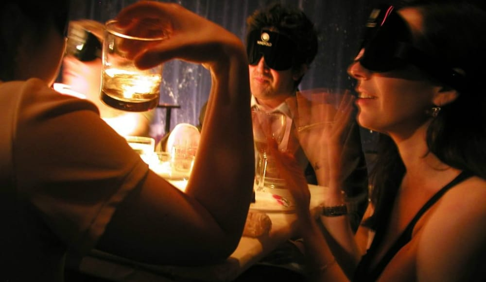 Guests dining blindfolded during a dinner in the dark experience