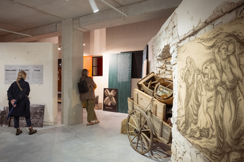 Visitors examining exhibits including a period cart and fresco-like wall artwork
