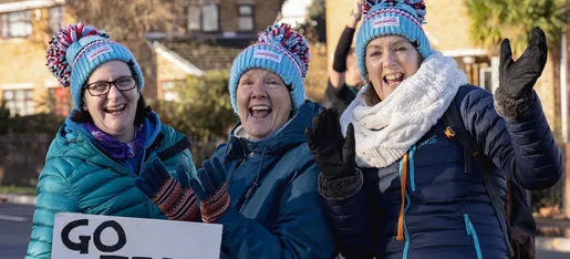Supporters in winter hats cheering on charity runners