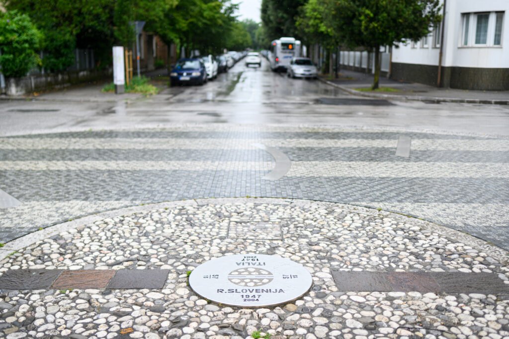 A stone marker in the street showing the 1947 border line between Slovenia and Italy