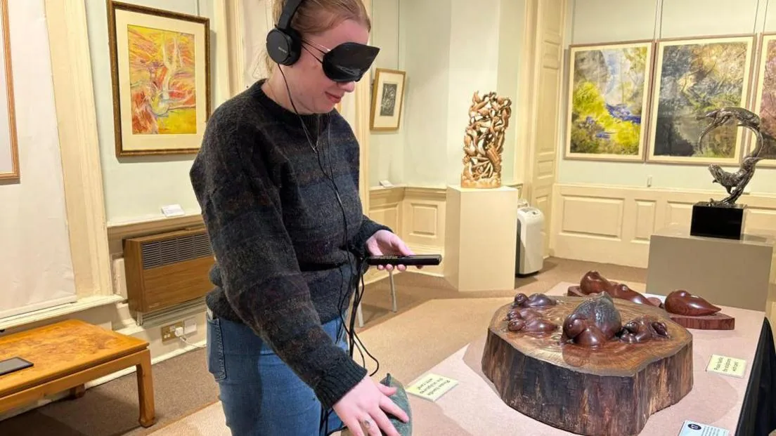 Visitor with blindfold experiencing tactile art