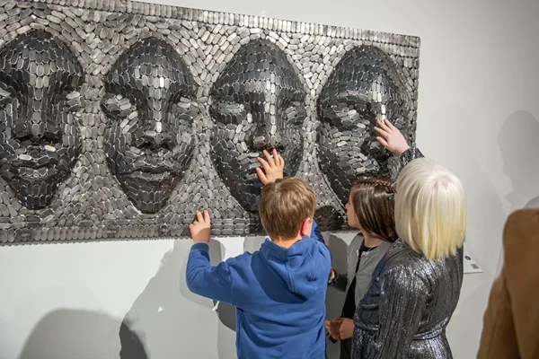 Visitors touching tactile artwork at the gallery opening