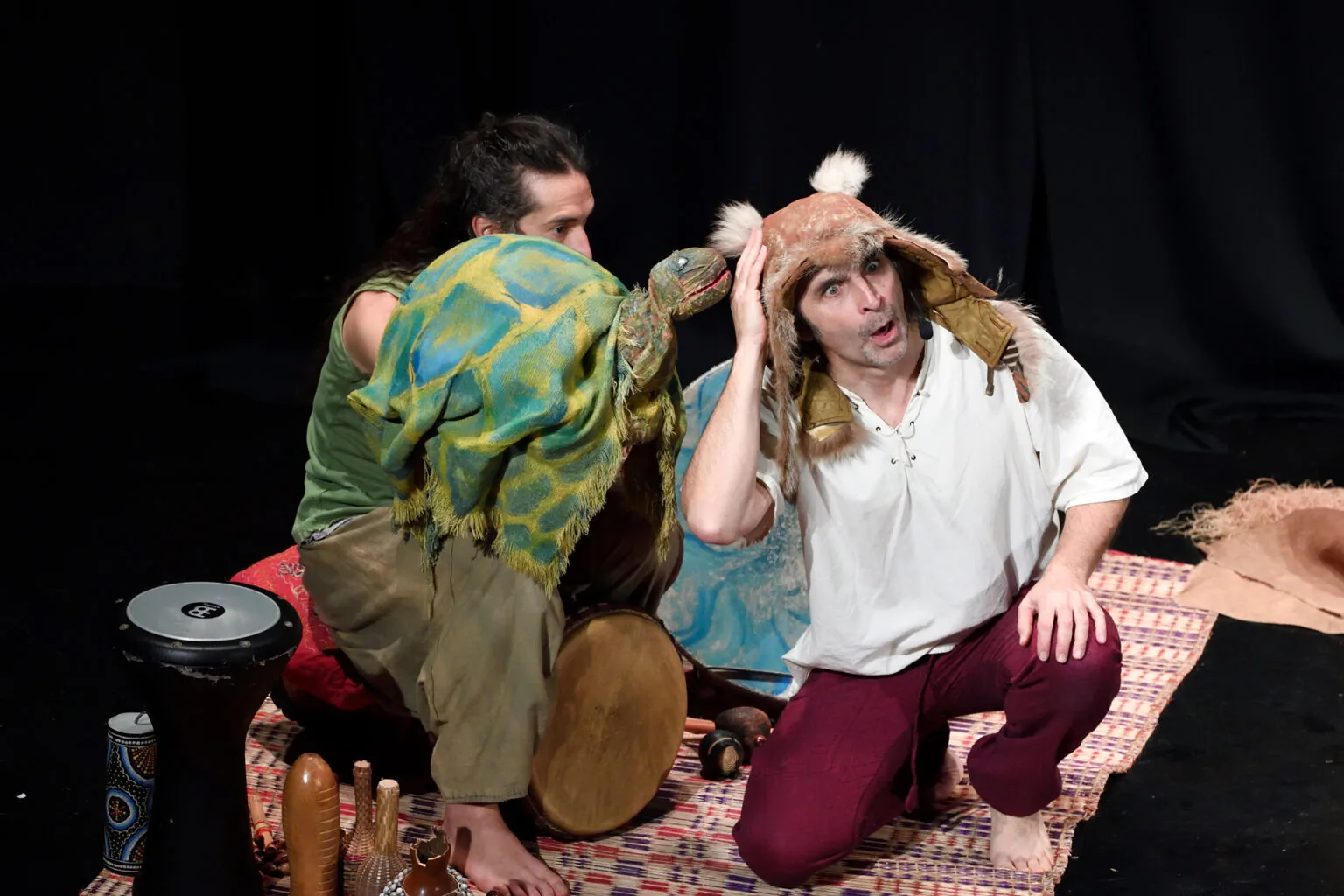 Actors with turtle puppet and African drums on stage during Il sogno di Tartaruga