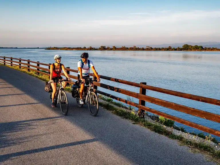 Cyclists riding along a scenic waterfront path in Friuli Venezia Giulia
